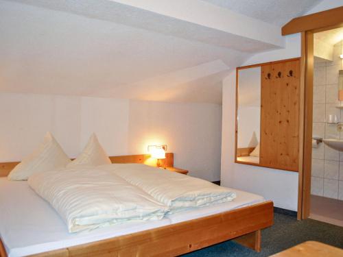 1 dormitorio con cama blanca y espejo en Holiday Home Ferienhaus Gaugg by Interhome, en Sankt Leonhard im Pitztal