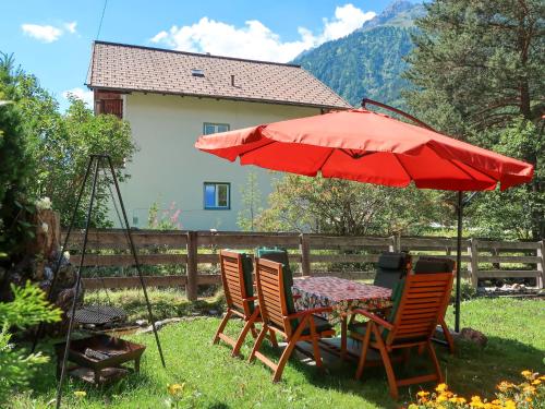 einen Tisch und Stühle unter einem roten Regenschirm im Hof in der Unterkunft Apartment Haflingerhof Almrose - KNT102 by Interhome in Kaunertal