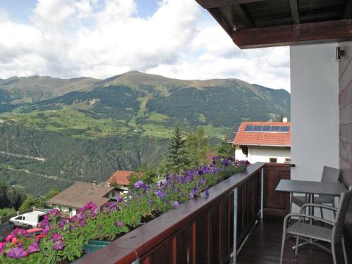 a balcony with purple flowers and mountains in the background at Apartment Alpenherz - PTZ430 by Interhome in Fendels