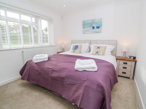 a bedroom with a purple bed with towels on it at Holywell Bay View in Newquay