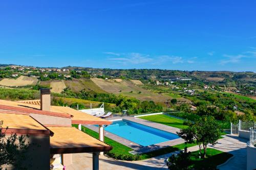 a house with a swimming pool next to a hill at Villa Lerant in Acquaviva Picena
