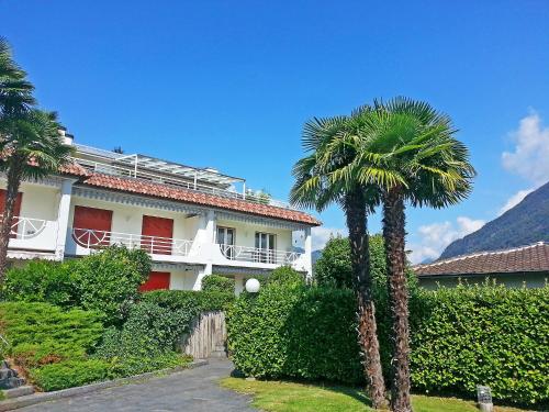 a building with a palm tree in front of it at Apartment Collina Verde B by Interhome in Ascona