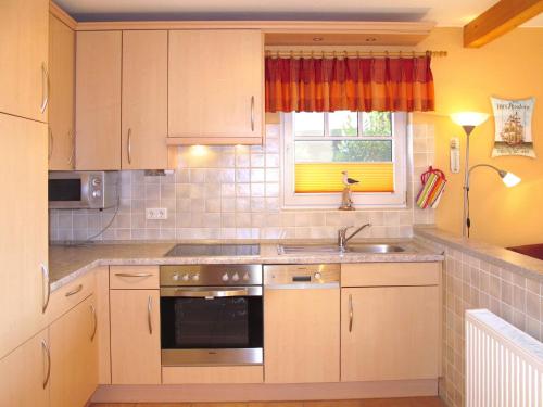 a kitchen with white cabinets and a sink and a window at Holiday Home Korsar II by Interhome in Burhave