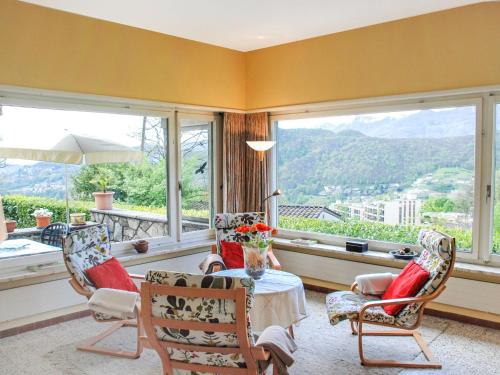 un soggiorno con tavolo, sedie e finestre di Holiday Home Cityview Lugano - Casa Carlo by Interhome a Cadro
