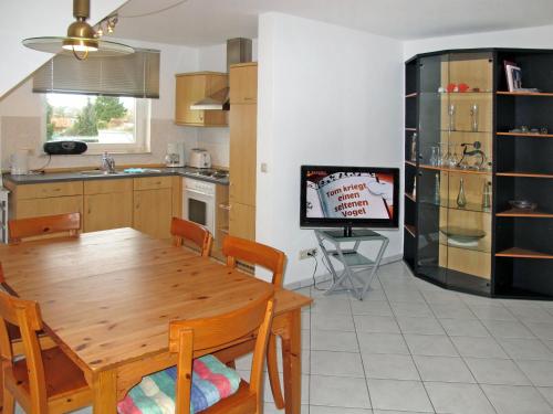 een keuken en eetkamer met een houten tafel en een televisie bij Apartment Gartenstraße-2 by Interhome in Ostseebad Karlshagen