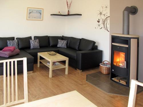 a living room with a black couch and a fireplace at Holiday Home Johannika by Interhome in Godern