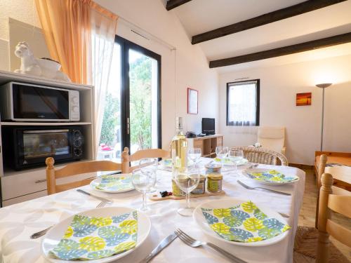uma sala de jantar com uma mesa com pratos e copos de vinho em Holiday Home Les Maisons de la Plage-8 by Interhome em Le Grau-du-Roi