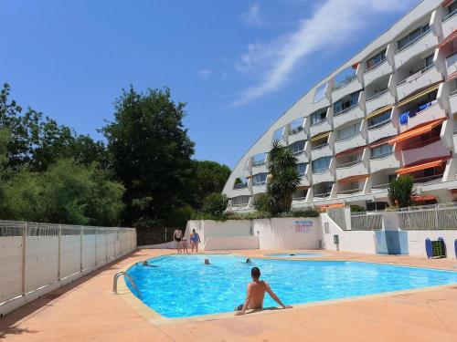 un homme dans une piscine en face d'un bâtiment dans l'établissement Apartment du Parc II-2 by Interhome, à La Grande Motte