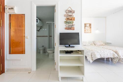 a bedroom with a bed and a television on a desk at Sunny Seaside Studio in Arroyo de la Miel