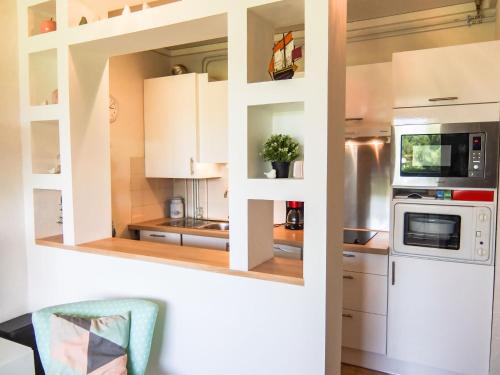 een keuken met witte kasten en een magnetron bij Apartment Les Catalanes du Golf by Interhome in Saint-Cyprien