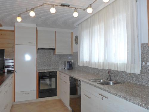 a kitchen with white cabinets and a sink at Apartment Chalet Almis 5 by Interhome in Grindelwald