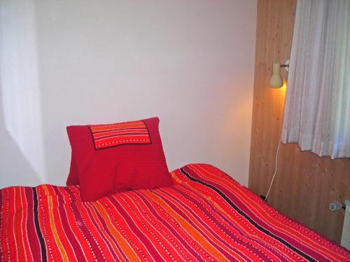 a red pillow sitting on top of a bed at Apartment Chalet Almis 5 by Interhome in Grindelwald