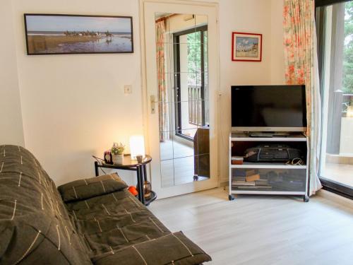 sala de estar con sofá y TV de pantalla plana en Apartment Le Fairway-1 by Interhome, en Deauville