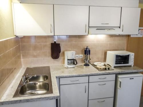 a kitchen with white cabinets and a sink and a microwave at Apartment Résidence jaune et rose-2 by Interhome in Marckolsheim