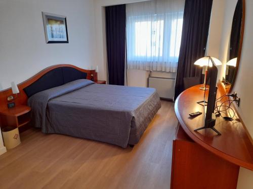 a bedroom with a bed and a desk with a television at Hotel Donizetti in Lallio