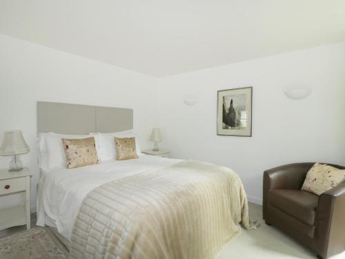 um quarto branco com uma cama e uma cadeira em Holemire Barn em Cockermouth