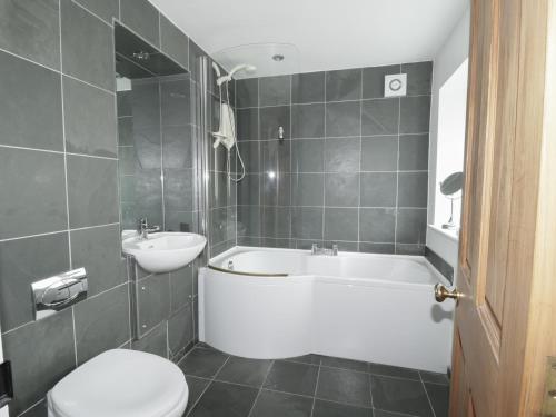 uma casa de banho com uma banheira, um WC e um lavatório. em Holemire Barn em Cockermouth