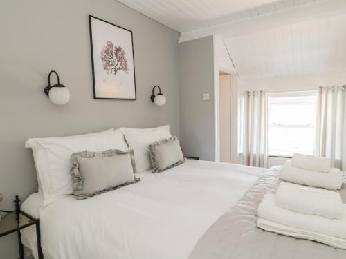 a white bedroom with a large white bed with pillows at Marsh Villa in Skinburness
