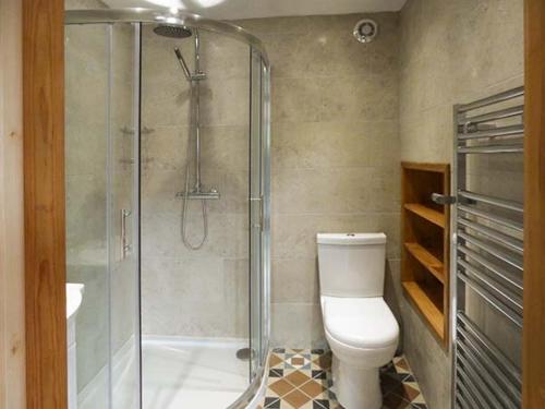 uma casa de banho com um WC e uma cabina de duche em vidro. em Town End Barn em Bradwell