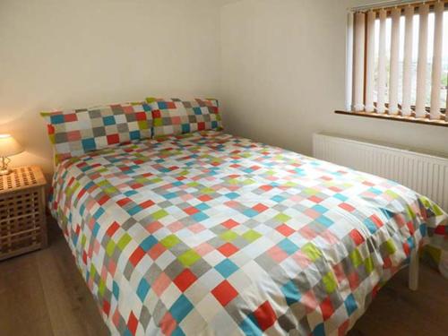 a bed with a colorful comforter in a bedroom at Town End Barn in Bradwell