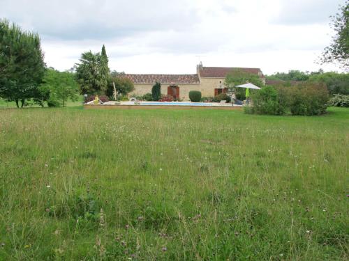 a field of grass with a house in the background at Holiday Home Le Coustal by Interhome in Blanquefort-sur-Briolance