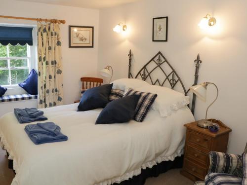 ein Schlafzimmer mit einem großen weißen Bett mit blauen Kissen in der Unterkunft Coachmans Cottage in Levens