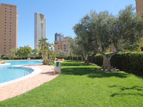 un parque con un árbol y un banco junto a una piscina en Apartment Coblanca-1 by Interhome, en Benidorm