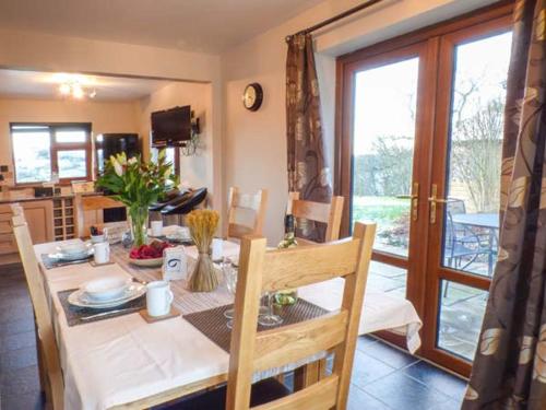 a dining room with a table and a kitchen at Tynddol Bungalow in Llanbadarn-fynydd