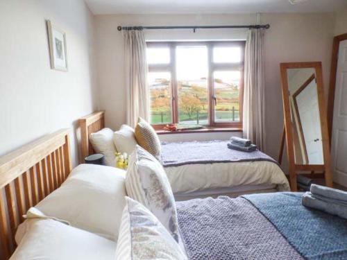 a bedroom with two beds and a window at Tynddol Bungalow in Llanbadarn-fynydd