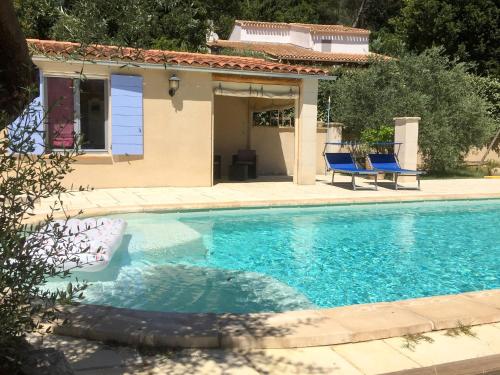 a swimming pool with two blue chairs next to a house at Holiday Home Sweet Home in Luberon - VLU100 by Interhome in Villelaure