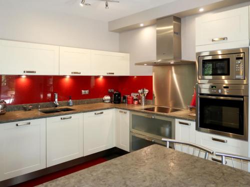 a kitchen with white cabinets and red walls at Holiday Home Sweet Home in Luberon - VLU100 by Interhome in Villelaure