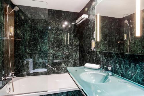 
a bathroom with a tub, sink and mirror at B&B Hotel Granada Estación in Granada
