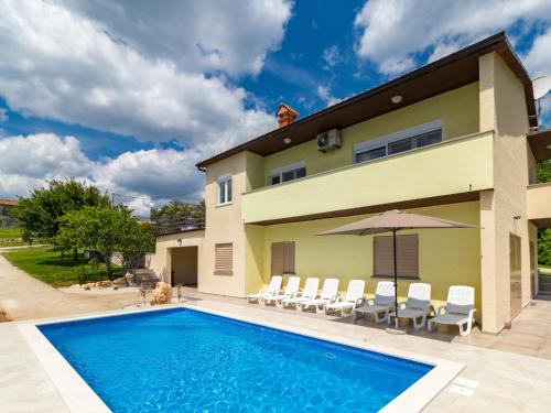 a pool in front of a house with chairs and an umbrella at Holiday Home Larisa - IPC141 by Interhome in Pićan