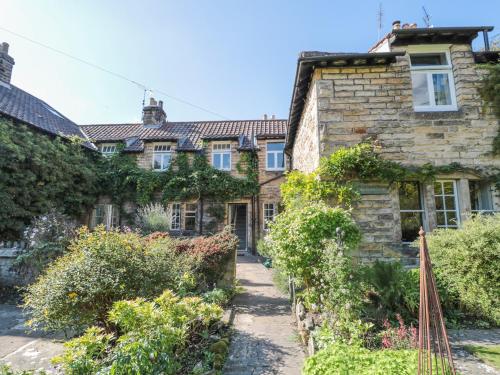 an old stone house with a garden in front of it at Teviot Cottage in Corbridge