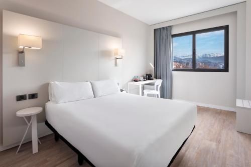 
a hotel room with a white bed and white walls at B&B Hotel Granada Estación in Granada
