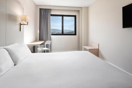 a hotel room with a large white bed and a window at B&B HOTEL Granada Estación in Granada