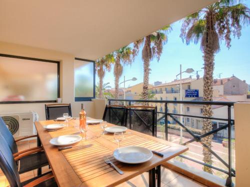 a dining room with a table and a balcony with palm trees at Apartment Le Magellan-2 by Interhome in Saint-Raphaël