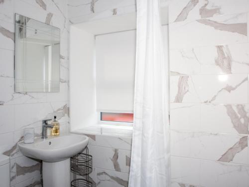 a white bathroom with a sink and a mirror at Carters Cottage in Chapel en le Frith