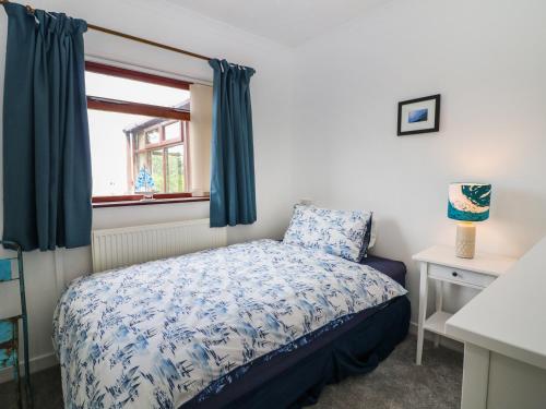 a small bedroom with a bed and a window at Eryl in Pwllheli