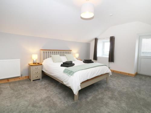 Un dormitorio con una gran cama blanca y una ventana en Ysgubor Fawr, en Caernarfon