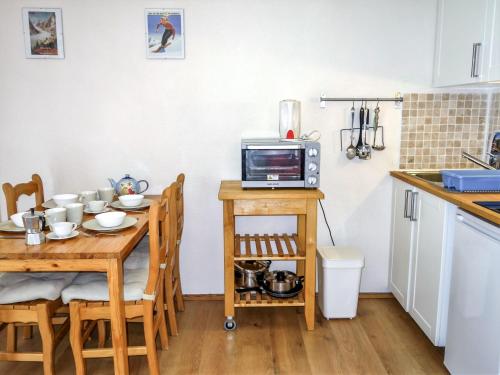 une cuisine avec une table et un four micro-ondes. dans l'établissement Studio L'Enclave I et J-28 by Interhome, aux Contamines-Montjoie