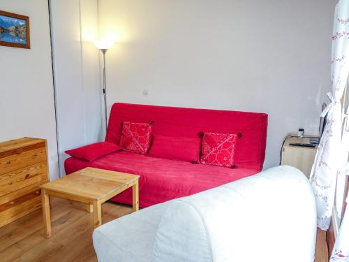 a red couch in a living room with a table at Studio L'Enclave I et J-28 by Interhome in Les Contamines-Montjoie
