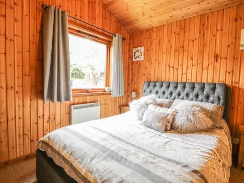 a bedroom with a bed in a wooden wall at 26 Dukes Meadow in Ellonby