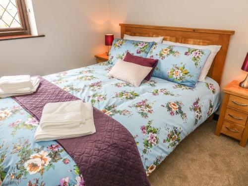 a bed with a blue comforter and pillows at Changegate Cottage in Keighley