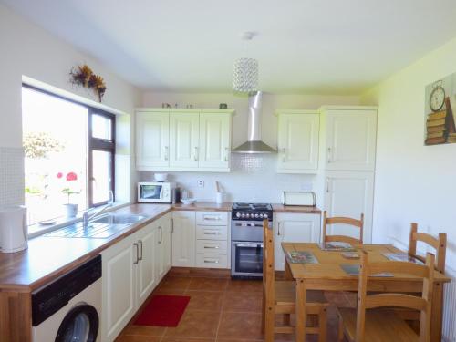 Una cocina con gabinetes blancos y una mesa de madera. en Nephin View, en Levally