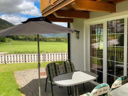 einen Tisch und Stühle mit Sonnenschirm auf einer Terrasse in der Unterkunft Apartment Top 1 by Interhome in Sankt Margarethen im Lungau