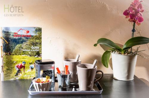 een blad met bekers en een plant op een tafel bij Hôtel Les Remparts in Nozeroy