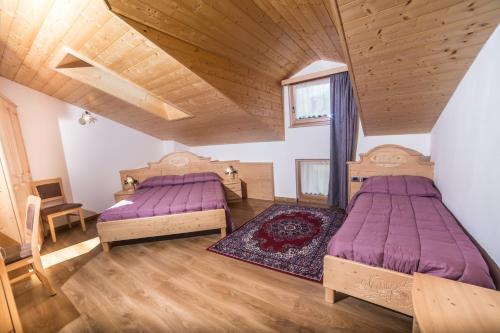 two beds in a room with wooden ceilings at Al Restelar in Cloz