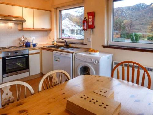 a kitchen with a wooden table and a kitchen with a stove and oven at 5 Innes-Maree in Poolewe