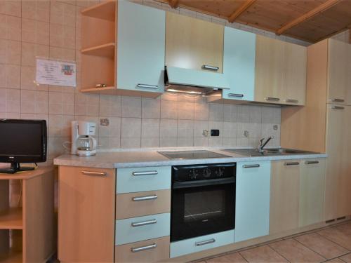 una cucina con mobili bianchi e un forno a piano cottura di Apartment Casa Crapena-2 by Interhome a Livigno